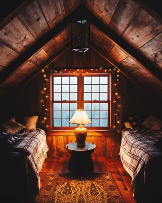 Фото Уютная комната на чердаке, освещаемая лампой и гирляндой