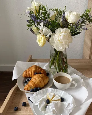Фото Чашка кофе, круассаны с ягодами и цветы в вазе