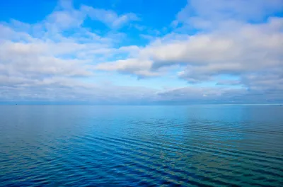 Облака над голубым морем в штиль - обои на телефон
