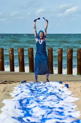Художник-перформанс молодой женщины в темно-синем платье, смазанном синими  красками гуаши, счастливо танцует на пляже. бодиарт и боди-арт. холст для  выразительной росписи гуашью индиго | Премиум Фото