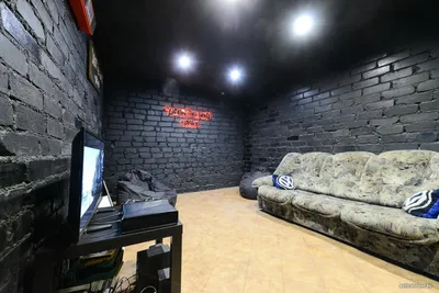 Дизайн гаража в темном стиле с диваном, телевизором и игровой приставкой