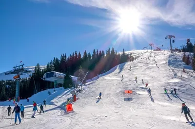 Словакия. зимний горнолыжный курорт ясна. яркое солнце в голубом небе над  горнолыжным склоном. подъемники и много лыжников | Премиум Фото