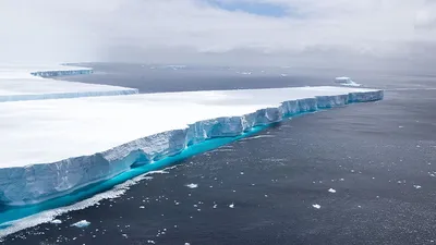 Айсберг, плывущий по воде у обрыва · Бесплатные стоковые фото