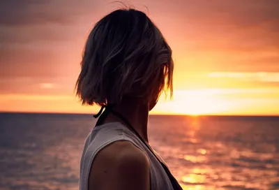 Женщина с короткими волосами стоит на набережной на берегу моря и смотрит  на вид — Контемпорация, пляж - Stock Photo | #224133460