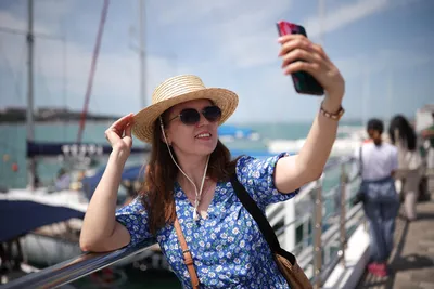 Молодая женщина в солнечных очках с помощью смартфона стоит на пляже |  Премиум Фото