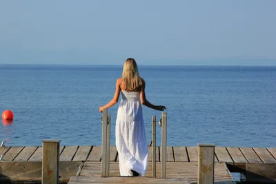 Вид сзади женщины фотографируя море с умным телефоном пока стоящ на корабле  против голубого неба Стоковое Фото - изображение насчитывающей шлем,  дистанционно: 154772304