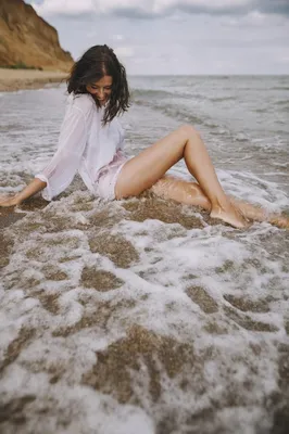 Мокрая белокурая девушка в белой рубашке сидел в воде и видом на море на  пляже на заре солнца. Концепция : Лето Стоковое Изображение - изображение  насчитывающей бобра, природа: 174356067