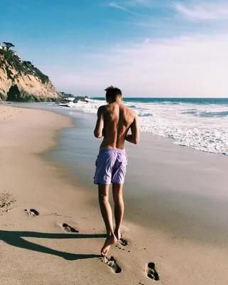Фото Мужчина стоит на пляже и снимает море