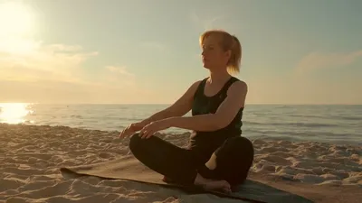 Женщина делает упражнения йоги на берегу моря · Бесплатные стоковые фото