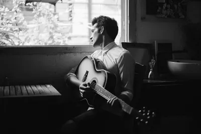 Мужчина музыканта сидит с гитарой Стоковое Фото - изображение насчитывающей  удерживание, утеха: 44027254