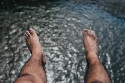 Женская нога в голубой воде. Ноги брызгают в бассейн. Голубая вода в  бассейне брызгает с женских ног. Женские ноги играют с водой в бассейне.  Женщина резвится в бассейне . стоковое фото ©Korchemkin