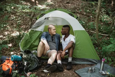 Разнообразные друзья отдыхают в палатке в лесу · Бесплатные стоковые фото