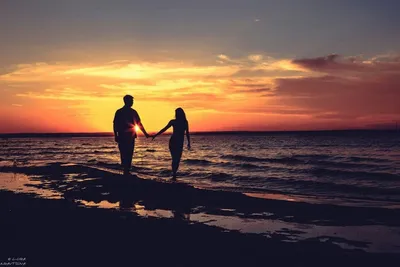 Силуэт пары, стоящей на берегу моря на закате · Бесплатные стоковые фото