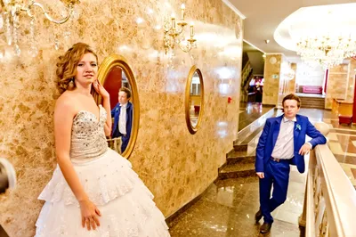 Жених в синем костюме и невеста в синем платье, стоя с бокалами в который  наливают шампанское Stock Photo | Adobe Stock