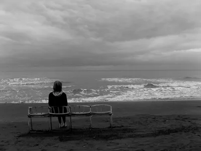 Молодая женщина сидит на берегу моря и смотрит вдаль. Концепция. Вид задние  девочки с длинное курчавым Стоковое Фото - изображение насчитывающей женщина,  наслаждение: 193100506